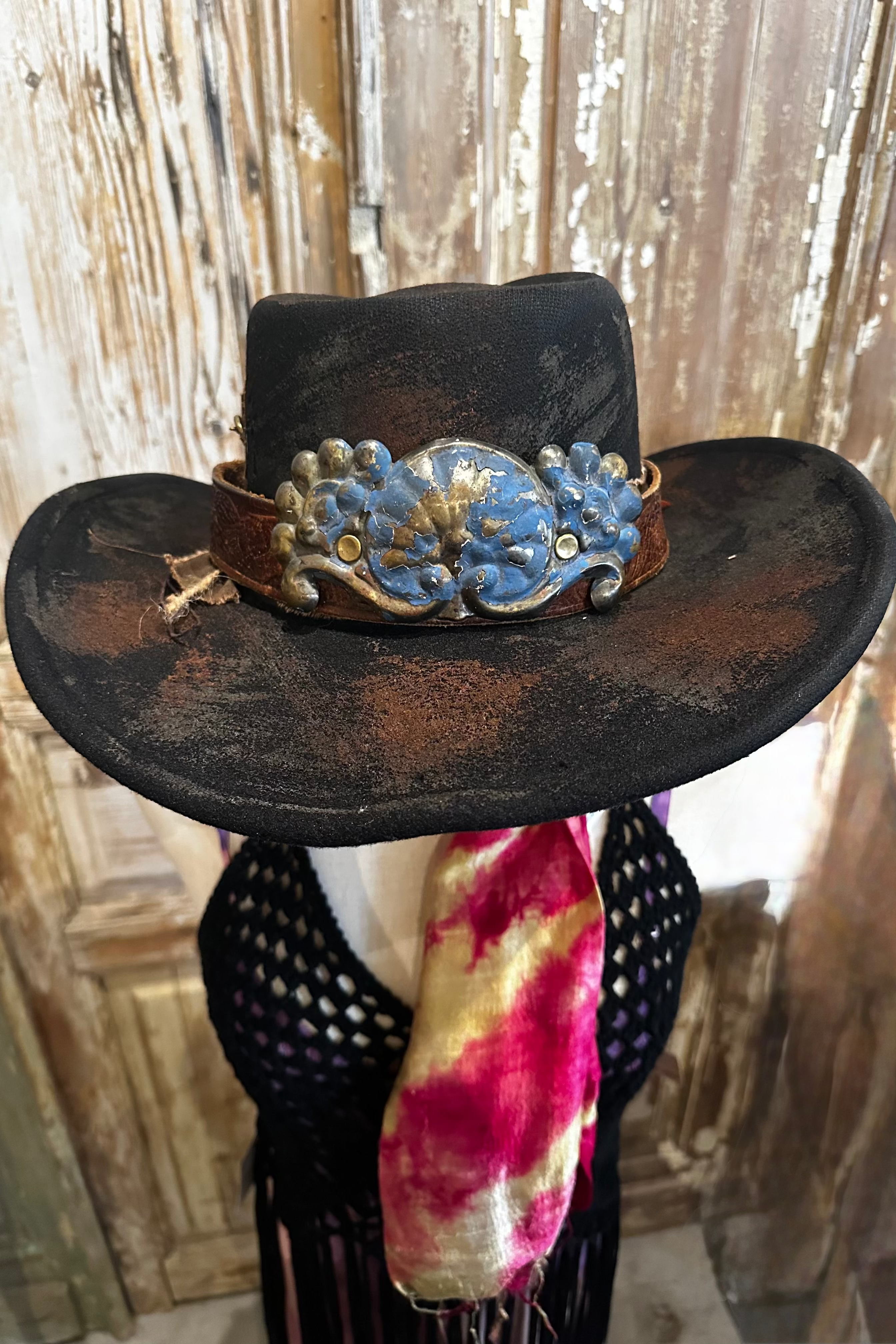 Black cowboy hat with decorative band on a wooden stand